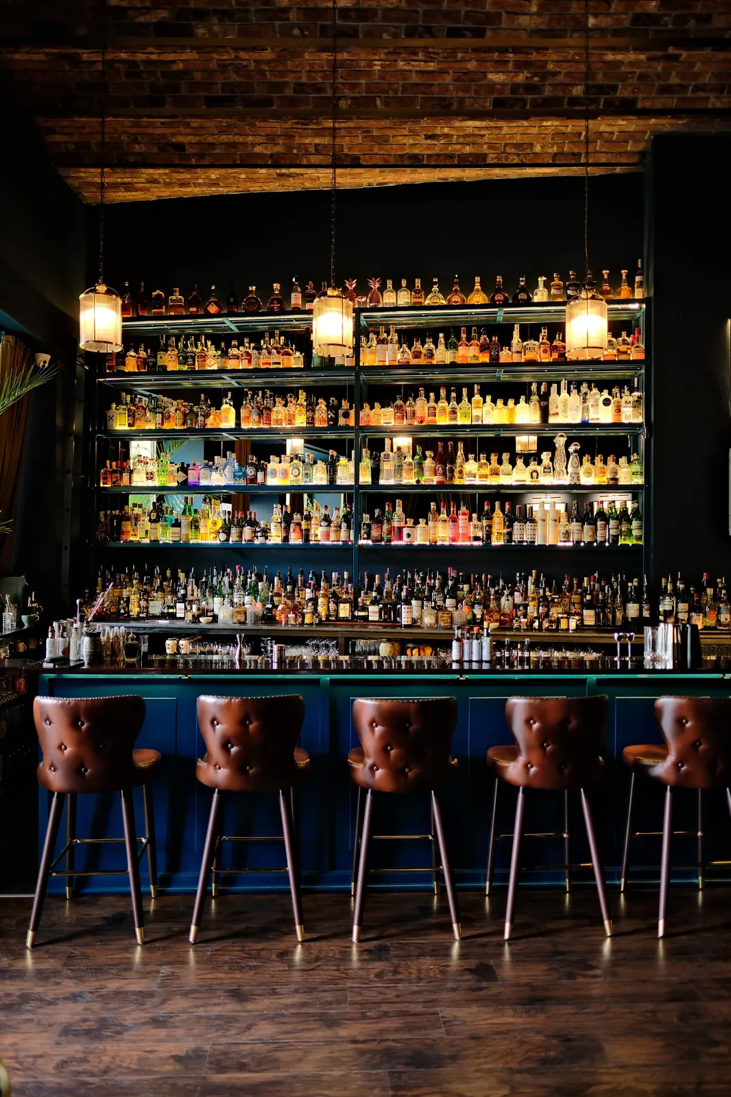 Back bar of Sippers cocktail bar in Bucharest Old Town, with hundreds of spirits and leather bar stools