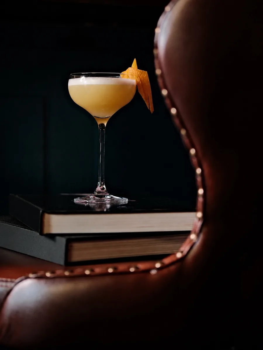 Signature sour cocktail on a stack of books at Sippers