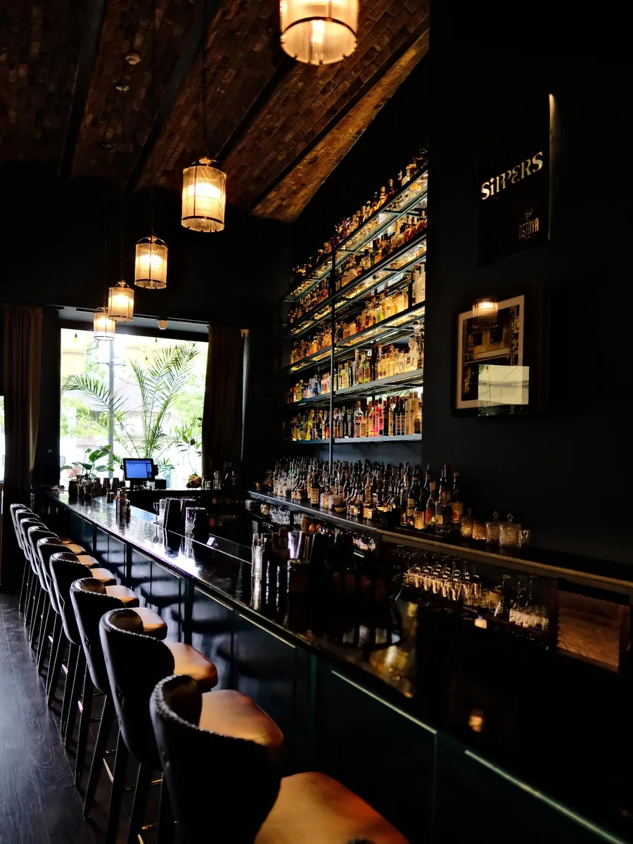 Inside Sippers cocktail bar with the lit back bar