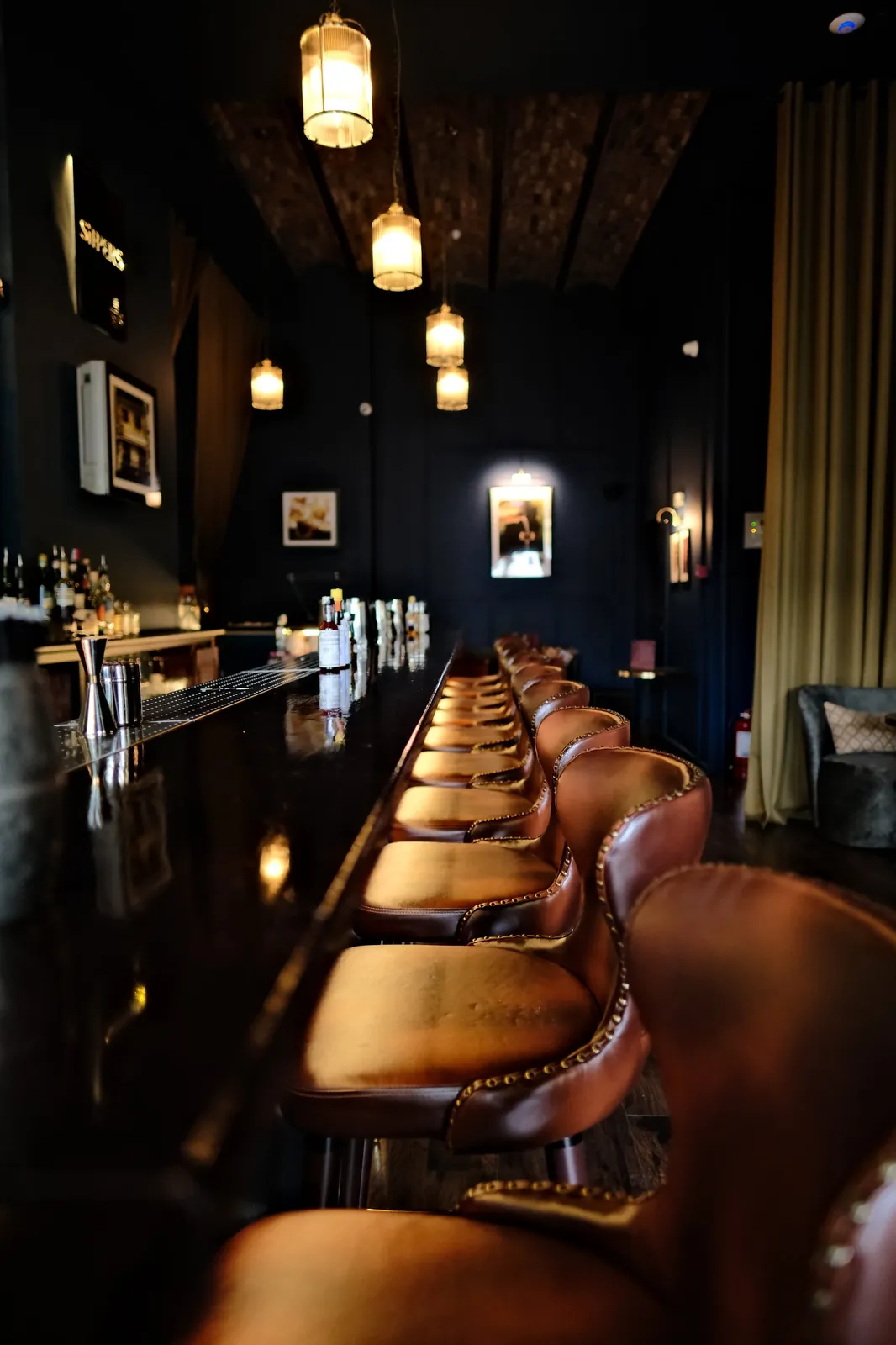 Row of leather bar stools along the Sippers bar counter in Bucharest Old Town