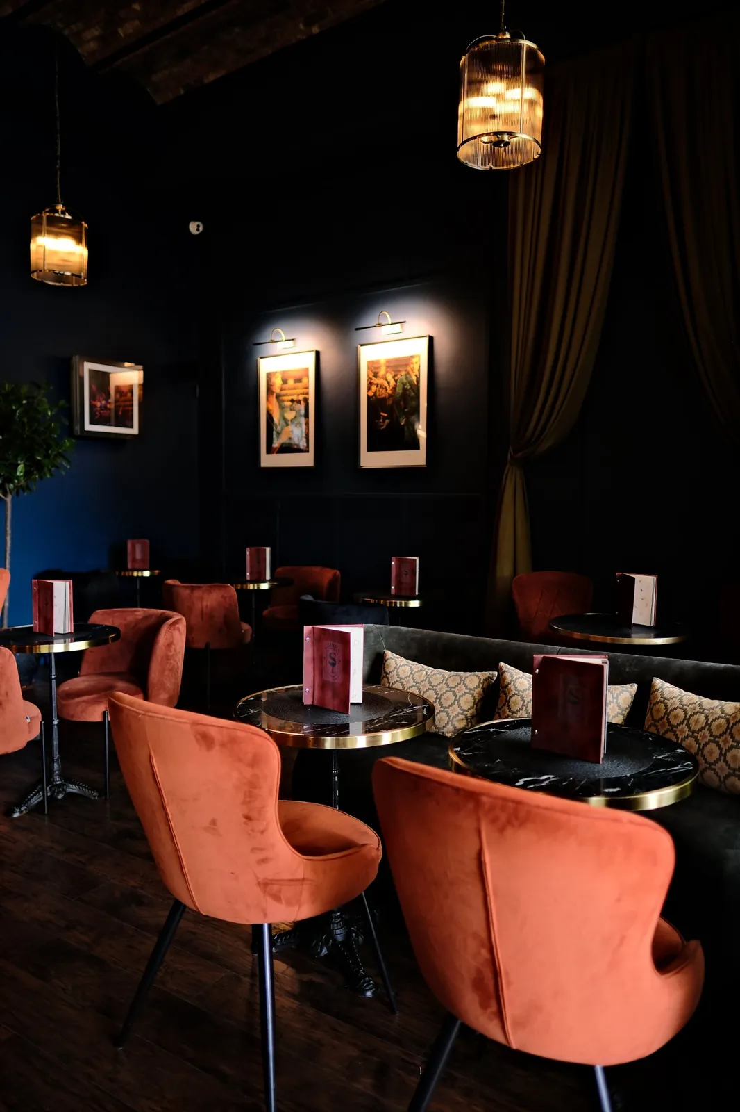 Lounge at Sippers cocktail bar with orange velvet chairs, marble tables and menus